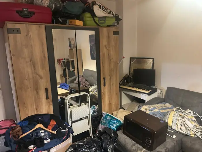 Zugestelltes Zimmer mit Schrank und Hausrat vor der Entrümpelung